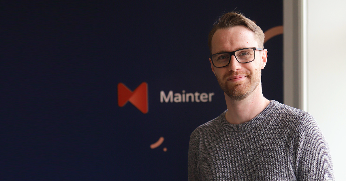 Mainters vd Kim Forsgren framför företagets logotyp, porträttbild i samband med ISO 27001-certifiering.