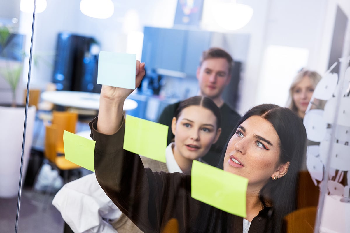 Tjej sätter upp post-it lappar på glasvägg