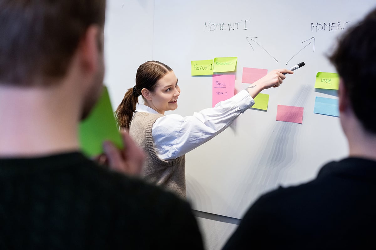 kvinna pekar med penna mot whiteboard